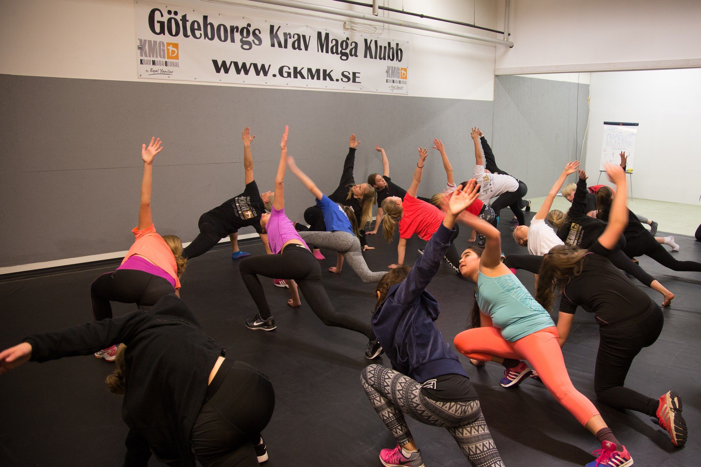 Uppvärmning på ett pass hos Göteborgs Krav Maga Klubb – deltagarna stretchar på mattan.